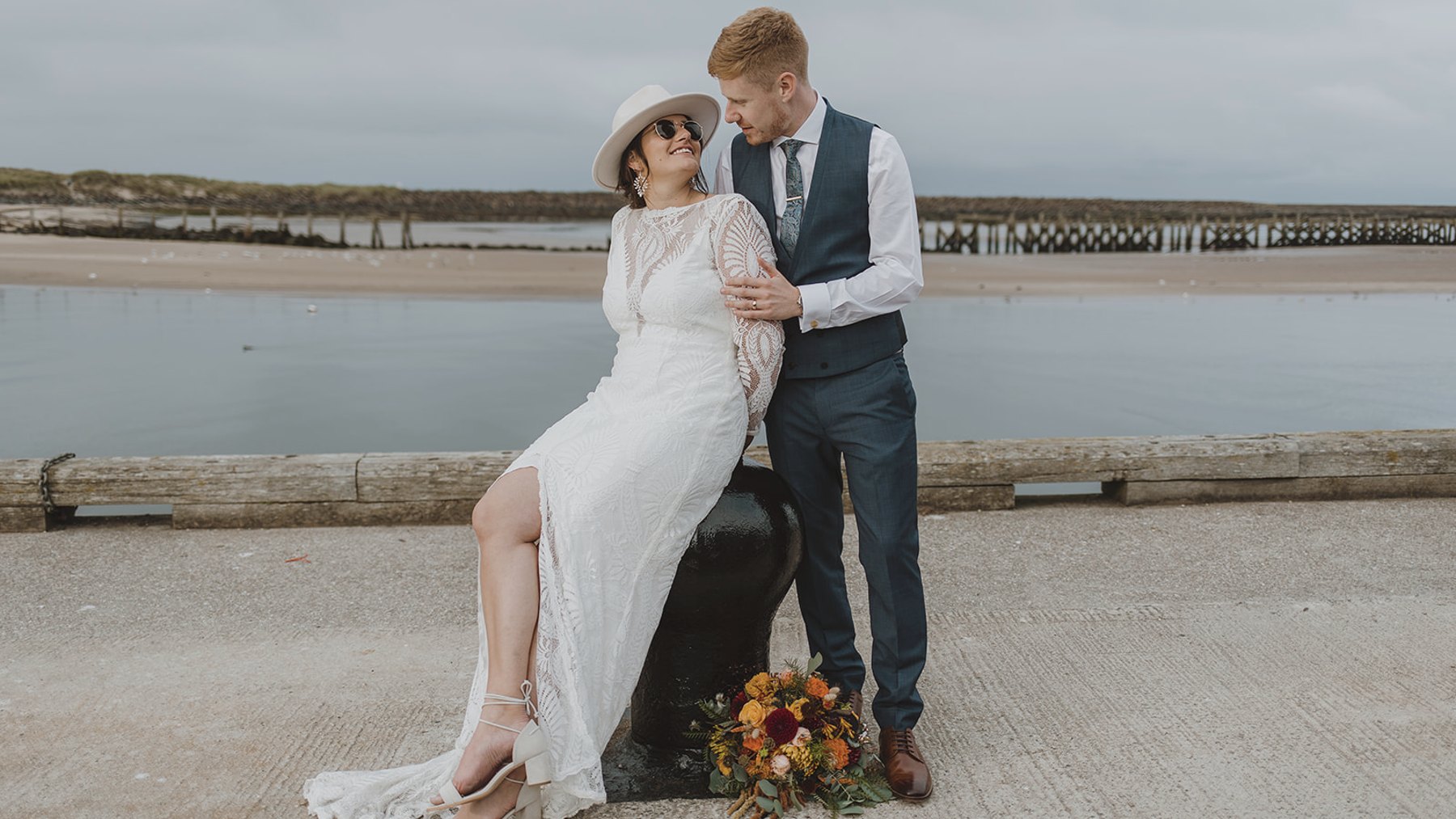 A couple on the harbour wall at Amble, Northumberland, on their wedding day